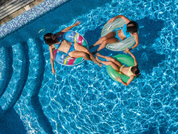 A picture of three people sitting in inflatable tubes in a swimming pool