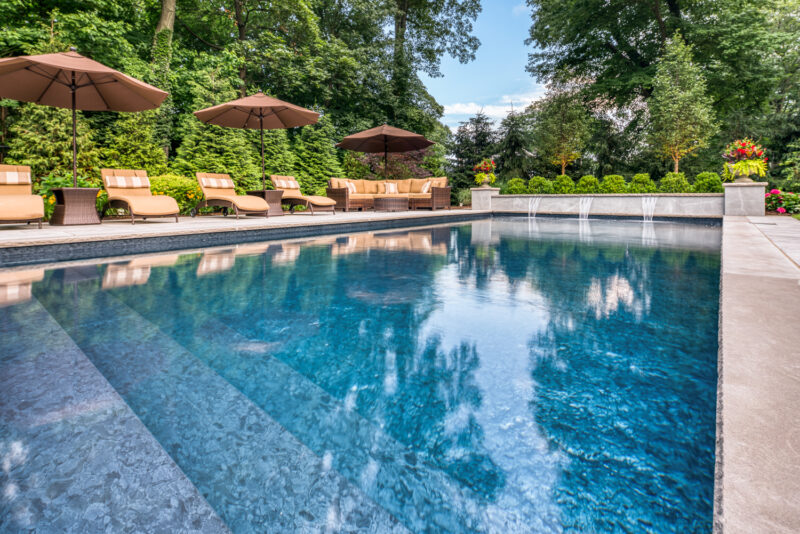 A vinyl liner pool with pool lounge chairs and umbrellas in the background