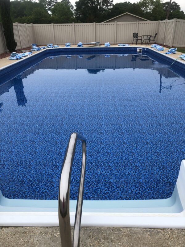 A picture of a rectangular fiberglass pool with an up-close view of a hand rail