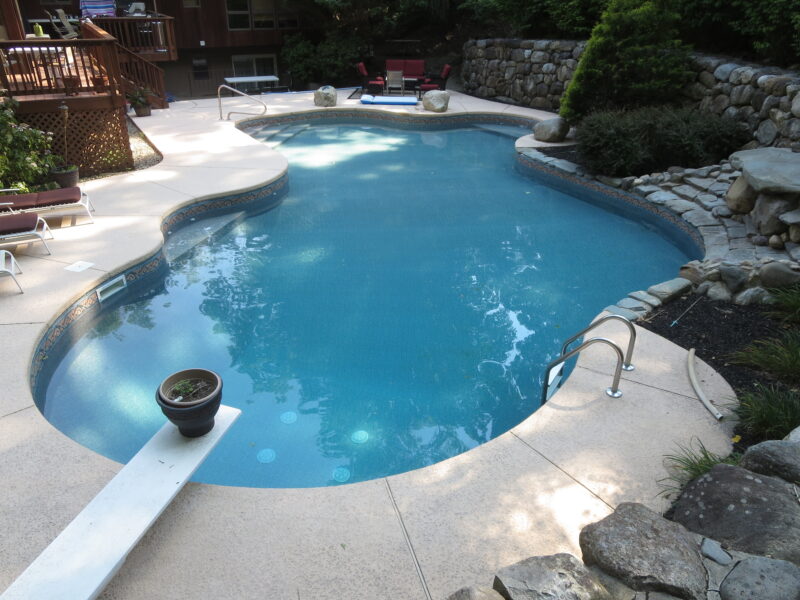 A picture of an oval-shaped pool with a diving board