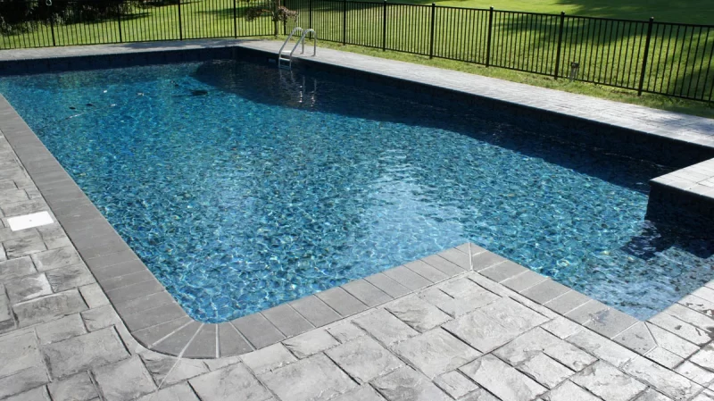 A blue pool with grey stones around the perimeter